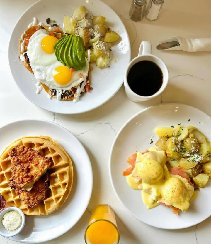 An overhead spread of benedicts, waffles and coffee